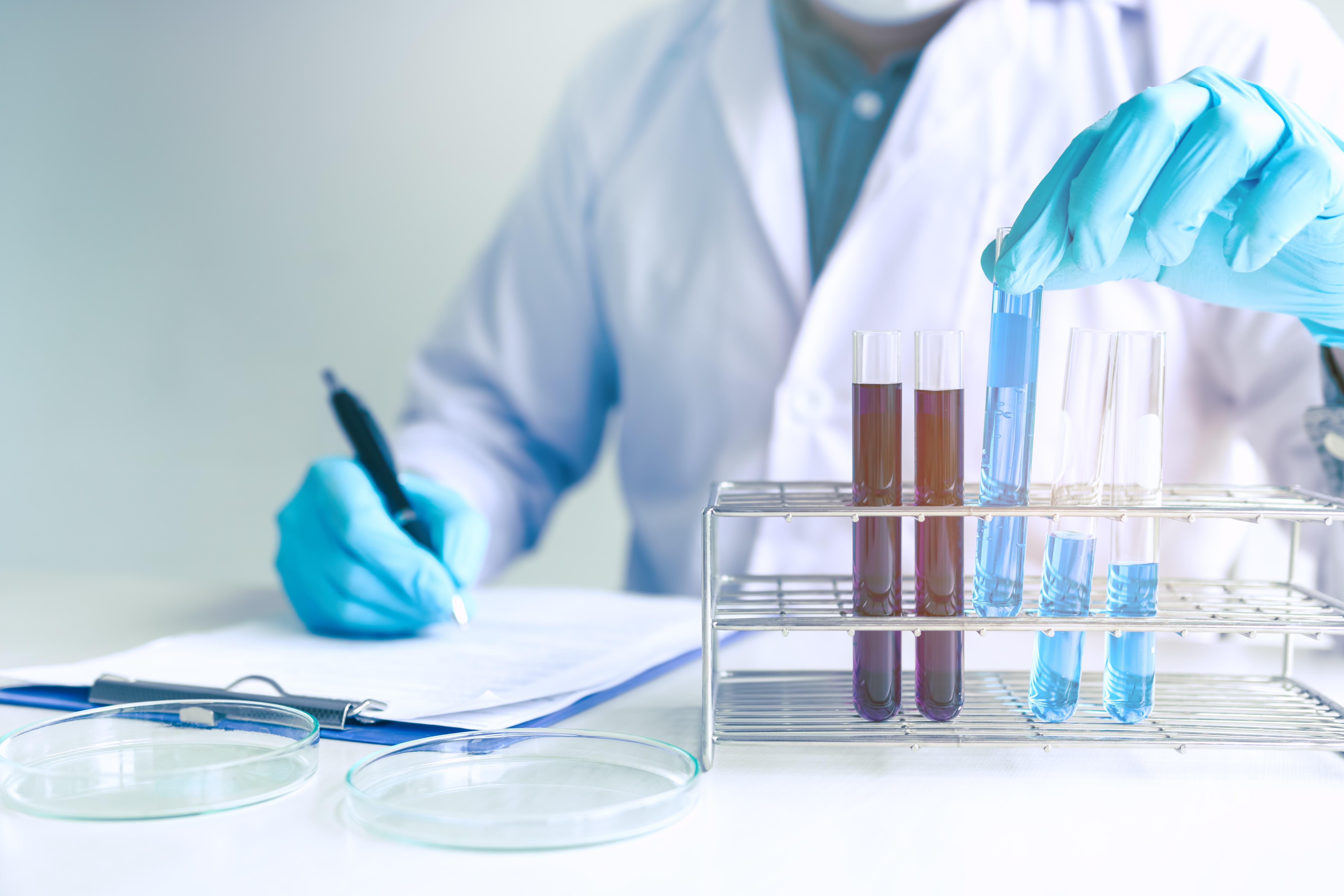 Male scientist worker in white coat working with test tubes in l